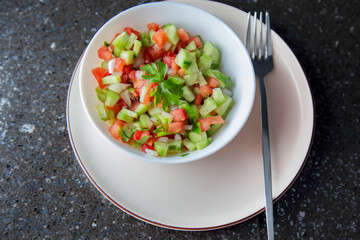 Fresh salad with cucumber, tomato, onion, parsley and olive oil close-up top view