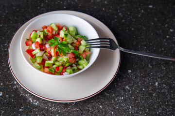 Fresh salad with cucumber, tomato, onion, parsley and olive oil close-up