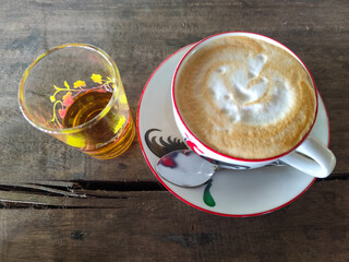 Hot espresso in a classic cup served with melted sugar on a wooden table.