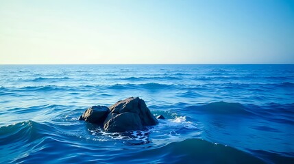 Fototapeta premium Serene Ocean Scene Dark Rocks Partially Submerged in Deep Blue Water Under a Clear Sky