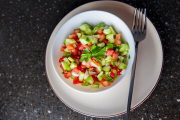 Fresh salad with cucumber, tomato, onion, parsley and olive oil close-up top view