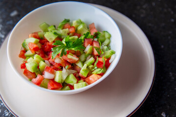 Fresh salad with cucumber, tomato, onion, parsley and olive oil close-up