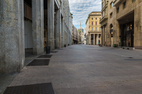 Milan city, Italy. Corso Vittorio Emanuele II in the historic center with the Milan Cathedral with the golden Madonnina in the background.  Very popular street full of shops