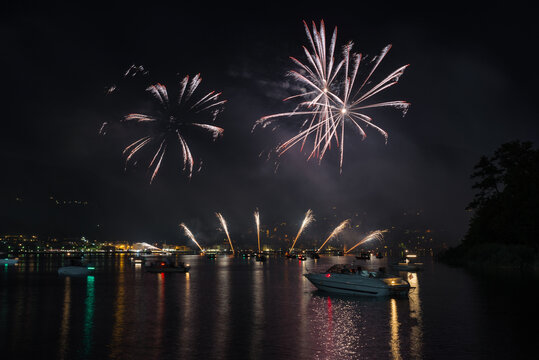 Fireworks at night over lake with boats. Ponte Tresa and lake Lugano with a fireworks display, northern Italy. Tourism and leisure concept