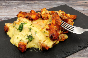 Portion of dirty cheesy fries on a slate serving board, fried battered skin on potato chips topped...