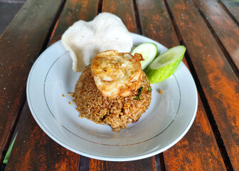 Delicious fried rice with vegetables and egg served on a wooden table.