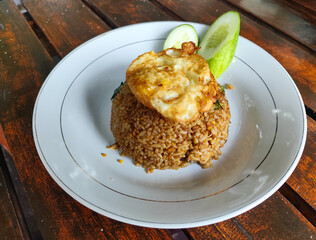 Delicious fried rice with vegetables and egg served on a wooden table.