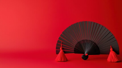 Elegant black fan with red tassels on red background minimalist art