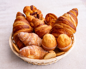 Sweet bakery products and croissant in the basket captured from above (top view), white background