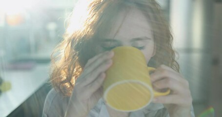 A woman enjoying the rich aroma of her coffee in a brightly lit kitchen, capturing the essence of a cozy morning