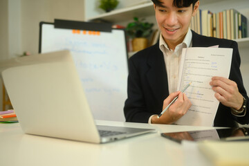 Smiling male tutor explaining a worksheet to student during an online learning session