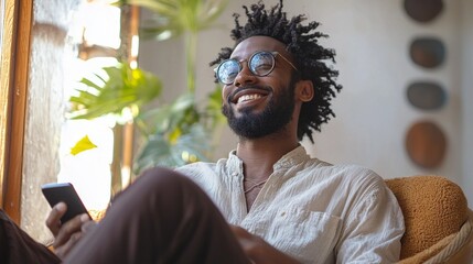 A man with glasses is sitting in a chair and holding a cell phone