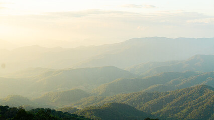 serene landscape showcasing rolling mountains under soft, hazy sky. lush greenery and gentle slopes...
