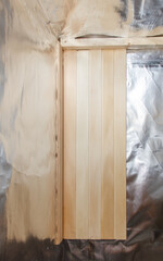 A wooden wall with a silver foil covering