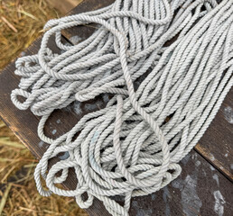 A bunch of grey ropes are laying on a wooden table