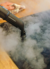 Close-up of a steam cleaner nozzle releasing steam onto induction stove . High quality photo