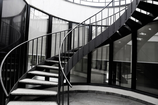 metal spiral staircase with rails, iron stairway in modern building with big windows. spiral Steel Staircase. metallic spiral stairs. house backdrop.