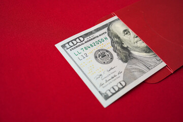 Lucky Asian chinese woman opening a red envelope gift, find large amount of money inside, one hundred united states dollars. Concept for Chinese New Year.