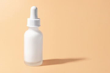 A frosted white dropper bottle with a minimalist design on a pastel peach background. Perfect for showcasing cosmetic products, branding, and packaging concepts