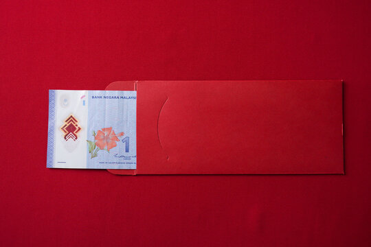 An unlucky Malaysian chinese woman opening a red envelope gift, only to find a very small amount of money inside, one ringgit. Concept for Chinese New Year.