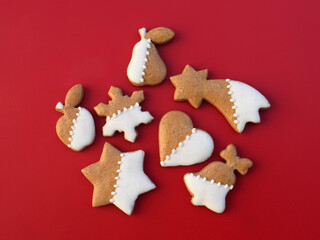 Decorated gingerbread cookies of various shapes on a red background. Christmas baking