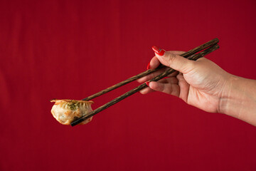 Asian women hand is picking dim sum using wooden chopsticks. Steamed dumplings for Chinese New Year...