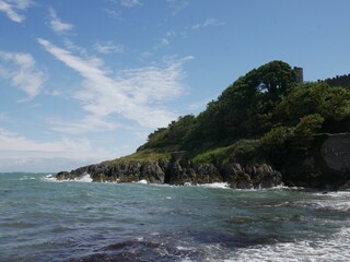 Scenic coastal landscape with castle ruin and blue sky.