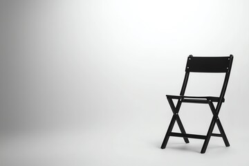 A minimalist black folding chair stands alone against a soft, neutral background, emphasizing simplicity and functionality.