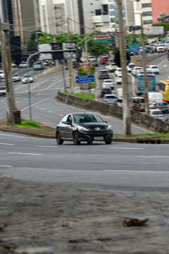 Black Peugeot 207 in movement, Compact hatchback cruising city freeway, Blurred background