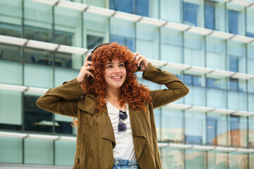 Young woman listening to music with headphones in urban background