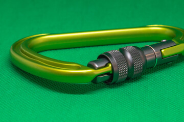 Metal yellow carabiner for rock climbing on green background, isometric view