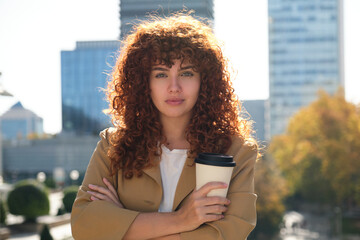 Confident businesswoman holding coffee outside office building