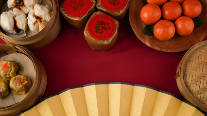 A flat lay photo of a red-clothed table featuring various traditional Chinese New Year dishes such...