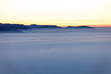 Ausblick auf das Nebelmeer im Tal. Am Horizont die Burg Hohenneuffen und die Achalm bei Reutlingen. Schwäbische Alb Albtrauf Silhouetten im Winter zur Blauen Stunde.