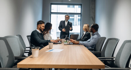 Meeting, sitting by the table. Group of office workers are indoors together