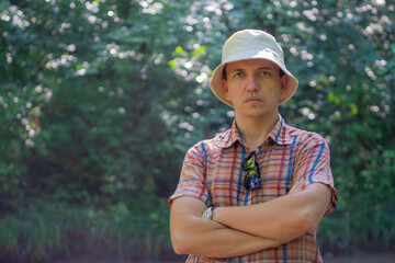 Chest portrait of young man in shirt against green defocused forest