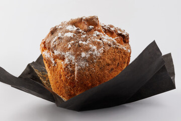 Muffin in an unfolded paper cup on a white background.