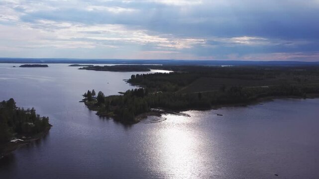 Aerial showing the swedish coastline during a sunny summer day, light rays shining through the clouds and the sunlight reflecting in the water
