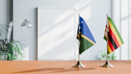 FLAGS OF SOLOMON ISLANDS AND ZIMBABWE ON TABLE