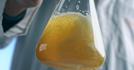 Super slow motion of lab worker mix beer into glass ware for quality testing, ensuring it meets production standards. The beer is carefully inspected in brewery with precision and dedication.