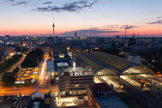 Ausblick auf Berlin mit der untergehenden Sonne am Horizont und der Berliner Fernsehturm Alex und dem Ostbahnhof. 