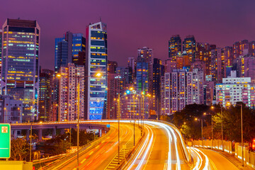 Hong Kong at night illumination of buildings and highway entrance to the bridge on skyscrapers near the bay