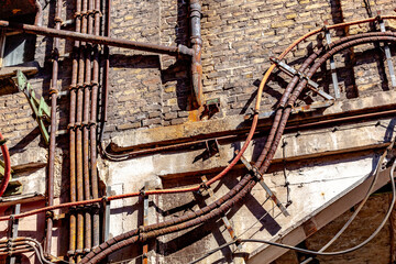detail of old industrial brick wall with rotten electric cables and tubes as symbol and lost place for industry