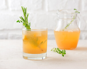 Fototapeta premium Pear drink, tea, lemonade, cocktail with lemon, rosemary, thyme and ice in a glass and jar. Healthy drink, sugar and alcohol free.