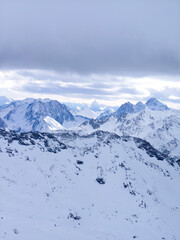 Snow-covered peaks and dramatic alpine scenery in Val Thorens, France. A stunning winter wonderland under a moody sky, perfect for ski enthusiasts and nature lovers.