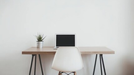 A minimalist workspace with a wooden table and chair, a clean white wall, and a laptop placed on the table.