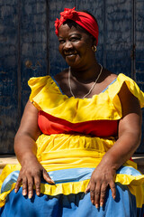 A Palenquera Woman Sitting On Stone Steps Wearing A Bright Dress in Cartagena, Colombia