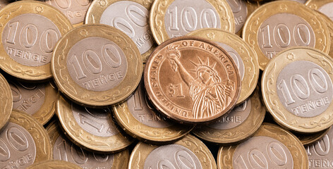 1 US dollar coin against the background of a 100 Kazakhstani tenge coin