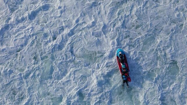 Aerial drone top down view of exciting water sports jet ski action with surfers riding waves in Nazare, Portugal