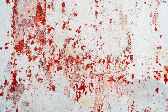 A weathered wall featuring peeling red paint on a white background. The distressed texture creates an abstract pattern with cracks, chipped areas, and uneven surfaces, making it ideal for projects